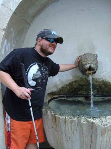 Tony next to a fountain with a lion's head